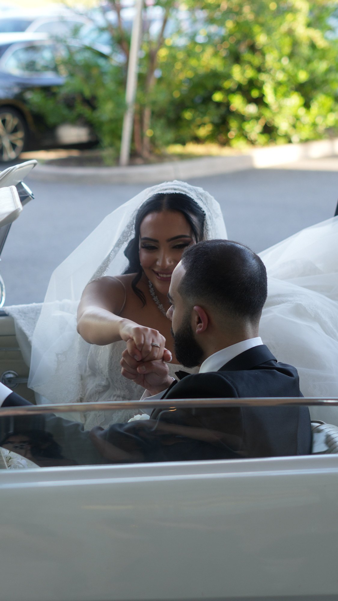 Groom kissing the bride's hand in a vintage convertible